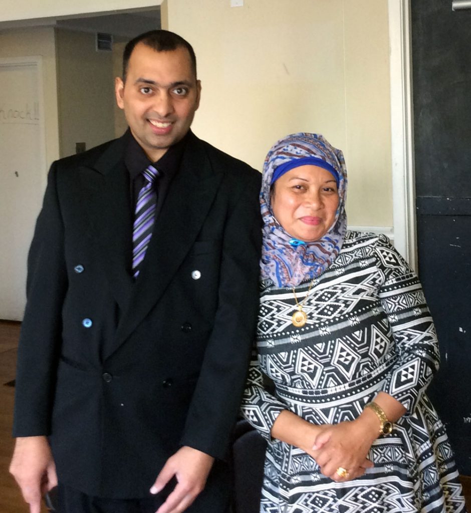 Shahrukh dressed in a suit standing beside his support worker